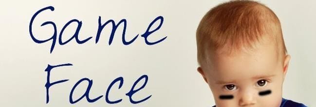 A baby with black streaks on his face and the words "Game Face"